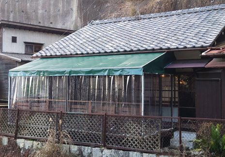 古民家レストランの庭にテラス席として天井膜付きのウッドデッキを設置、また周囲に雨除け・防寒のための透明ビニールカーテンも設置しています