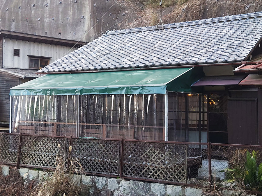 古民家レストランの庭にテラス席として天井膜付きのウッドデッキを設置、また周囲に雨除け・防寒のための透明ビニールカーテンも設置しています